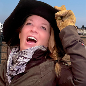 Woman in cowboy hat smiling outdoors.